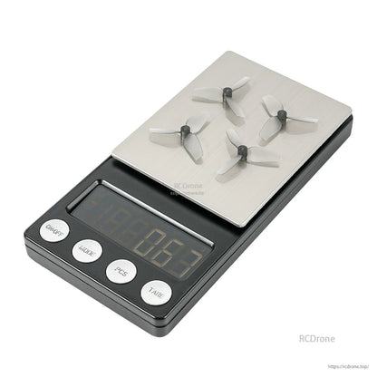 Four 3-blade micro propellers shown on a digital scale for weight reference