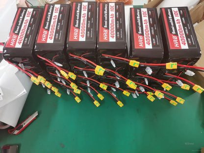 Bulk lot of HRB 40000mAh semi-solid battery packs with multiple XT90 connectors laid out on workbench