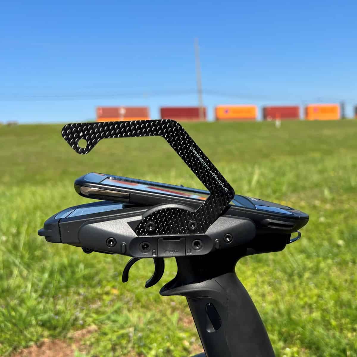 Carbon fiber carry handle installed on Futaba-style pistol grip RC transmitter, side profile outdoors