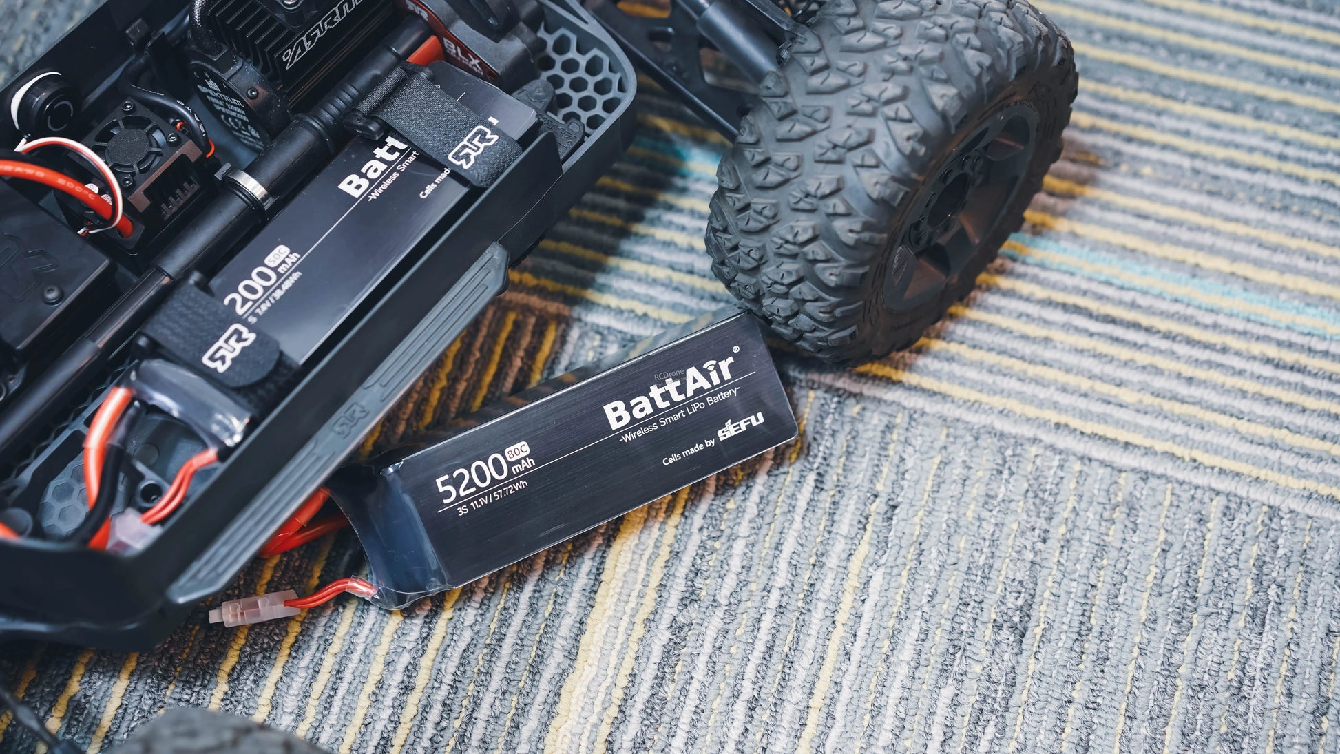 ISDT BattAir Smart 3S 5200mAh 80C LiPo battery pack with connector lead, next to an RC car chassis
