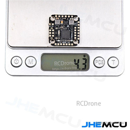 Flight controller weight shown on digital scale, 4.9 g reading with board on platform
