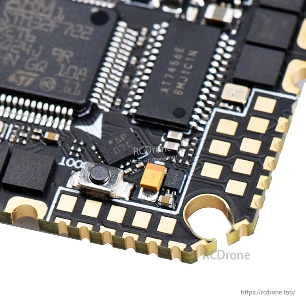 Close-up of onboard boot button and nearby chips on the flight controller PCB with gold solder pads