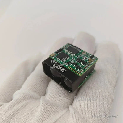 Compact laser rangefinder module with dual lenses, green circuit board, and UART interface.