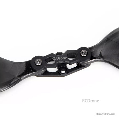 Close-up of a glossy carbon fiber folding propeller hub with bolted hinge and two blades