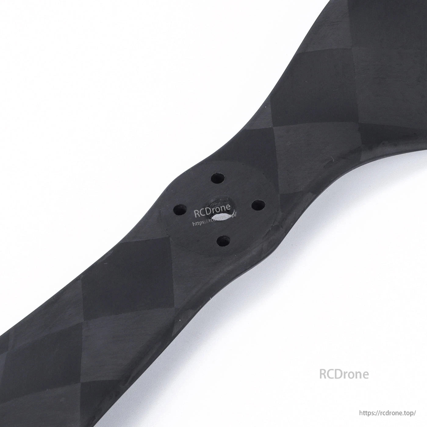 Close-up of carbon fiber drone propeller hub with four mounting holes and woven finish