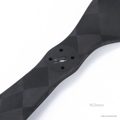 Close-up of carbon fiber drone propeller hub with four mounting holes and woven finish