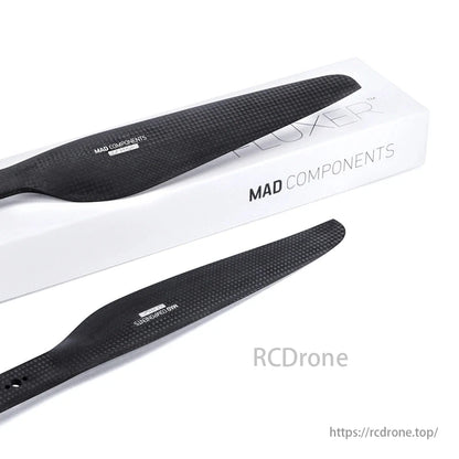 Black MAD COMPONENTS propellers with a textured surface, paired with a white FLUXER™ box, are designed for drones.