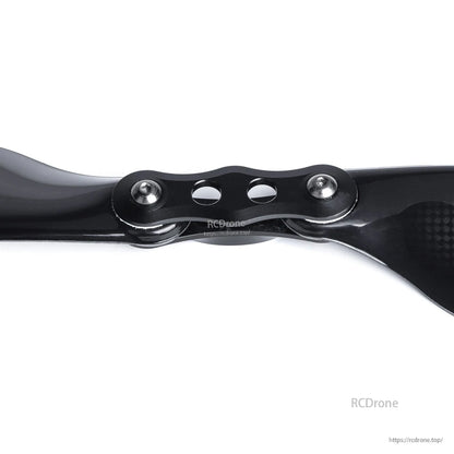 Close-up of a glossy carbon fiber folding multirotor propeller hub with two blades and mounting screws