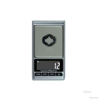 Small black circular ring part on a digital pocket scale reading 1.2 g
