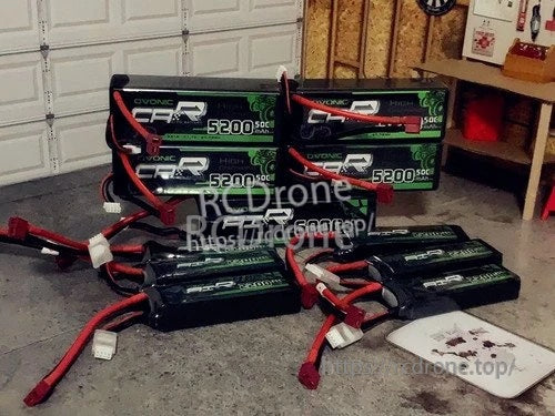 Several Ovonic LiPo battery packs with Deans-style T plugs and balance leads laid out in a garage