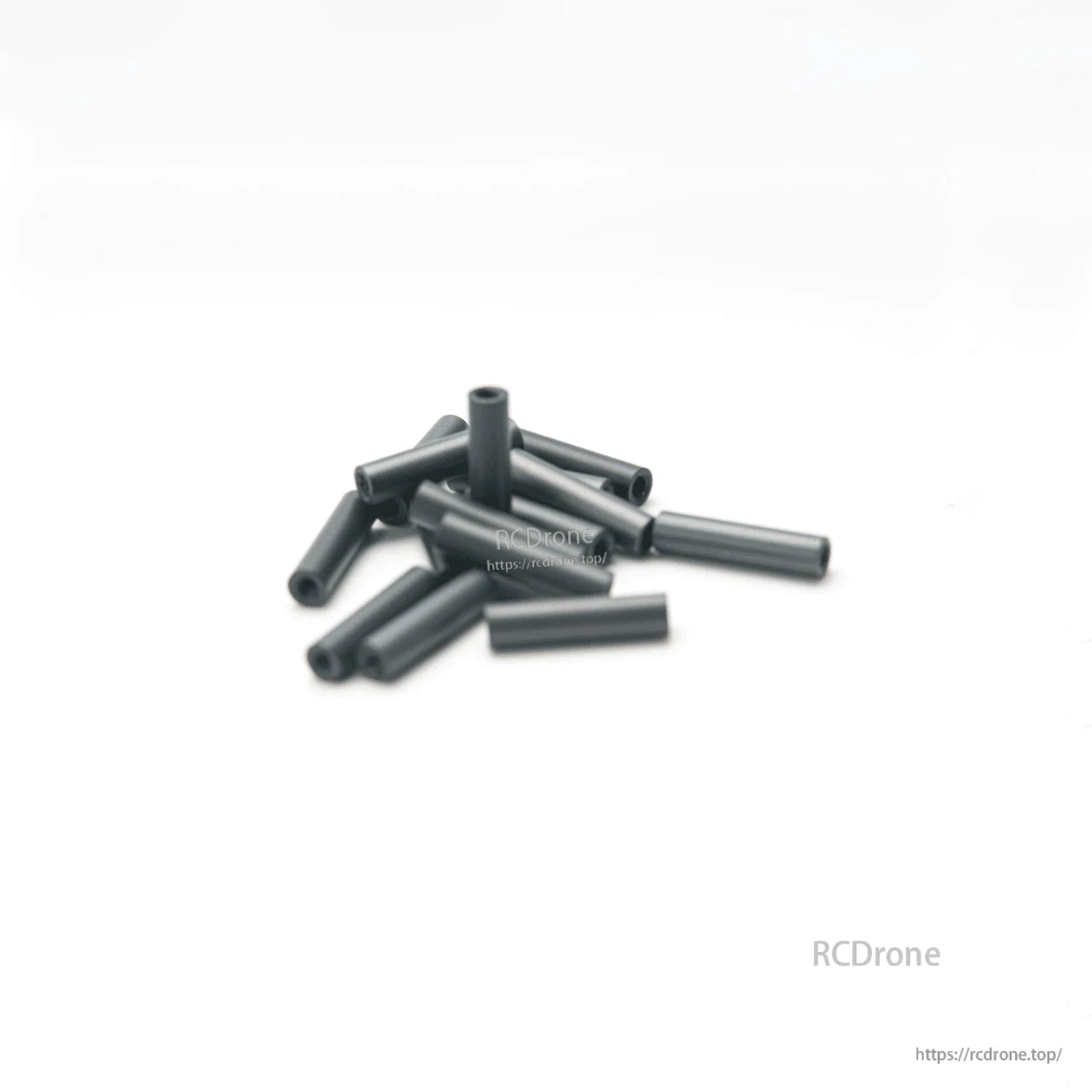 Pile of black aluminum hollow standoffs/spacers on white background, angled view