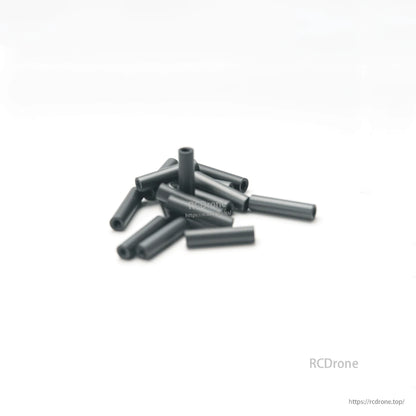 Pile of black aluminum hollow standoffs/spacers on white background, angled view