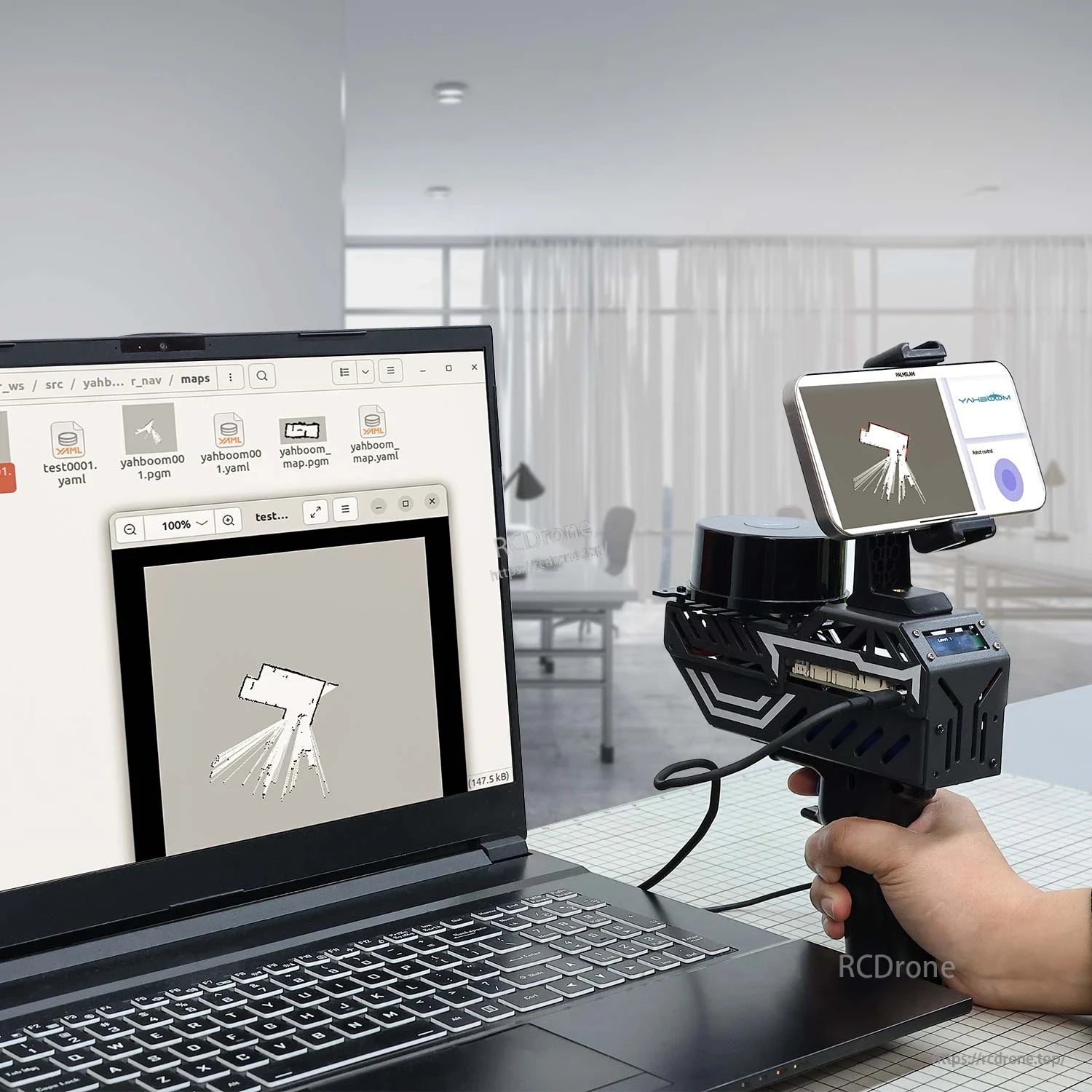 Handheld scanner connected to a laptop displaying a 2D SLAM map, with phone mounted on top