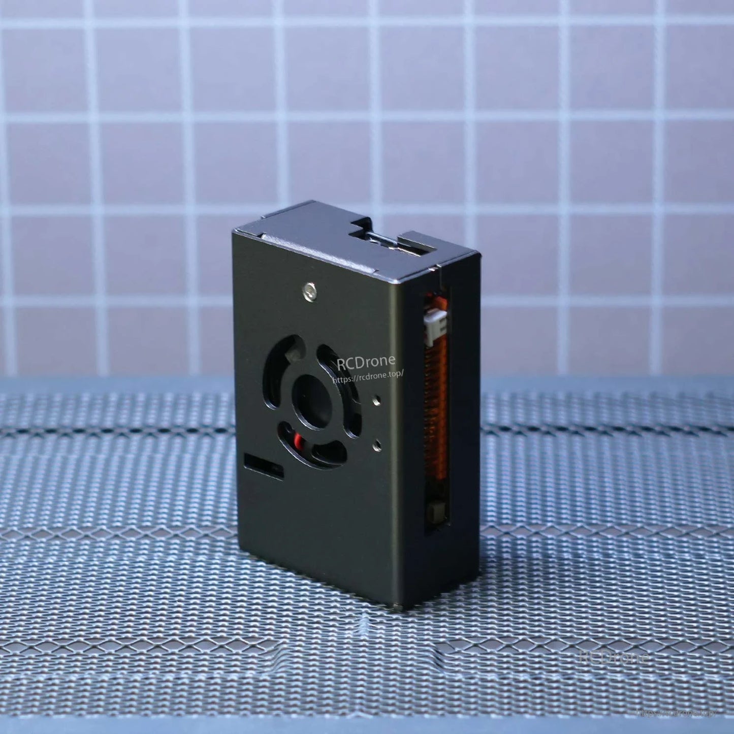Standing side view of the metal case showing top vent cutout and slim profile on textured surface