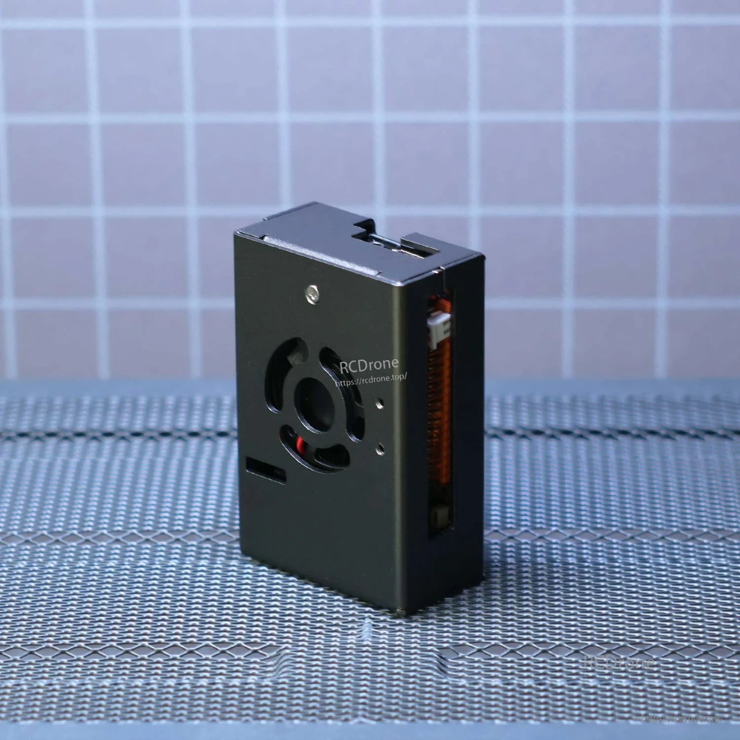 Standing side view of the metal case showing top vent cutout and slim profile on textured surface