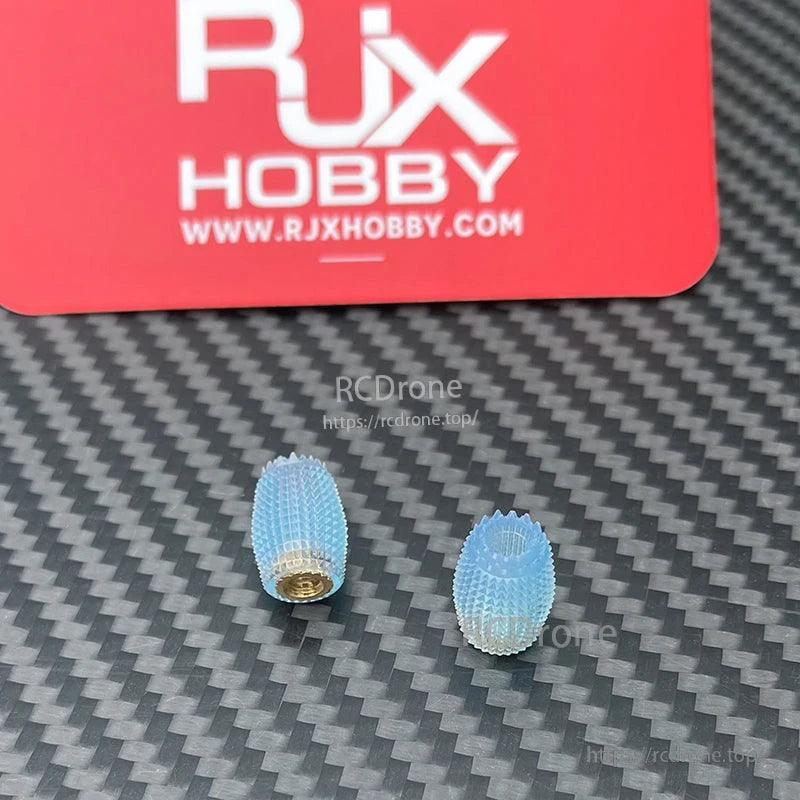 RJX 1 Pair Thumb Grippies Non-Slip Radio Stick, Pair of RJX Hobby blue textured thumb grippies for RC radio transmitter sticks on a carbon-fiber surface