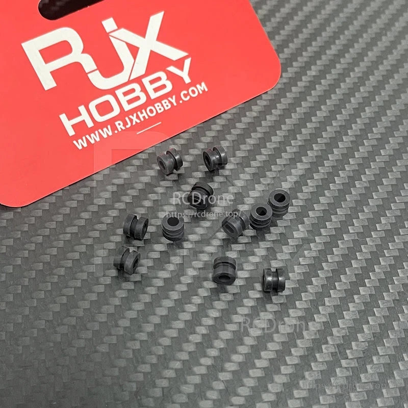 RJX 100pcs 3x5x6mm Damping Ball, Small black rubber RJX damping balls/grommets on a carbon fiber surface for RC vibration isolation