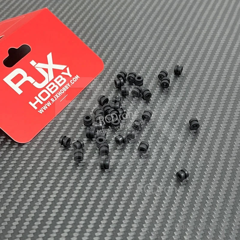 RJX 100pcs 3x5x6mm Damping Ball, RJX Hobby black rubber damping balls (3x5x6mm) assortment scattered on a carbon-fiber surface