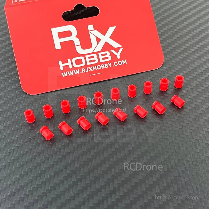 RJX 100pcs 3x5x7mm Damping Ball, RJX Hobby red damping ball bushings for RC models, small cylindrical vibration-damping inserts on a carbon-look surface