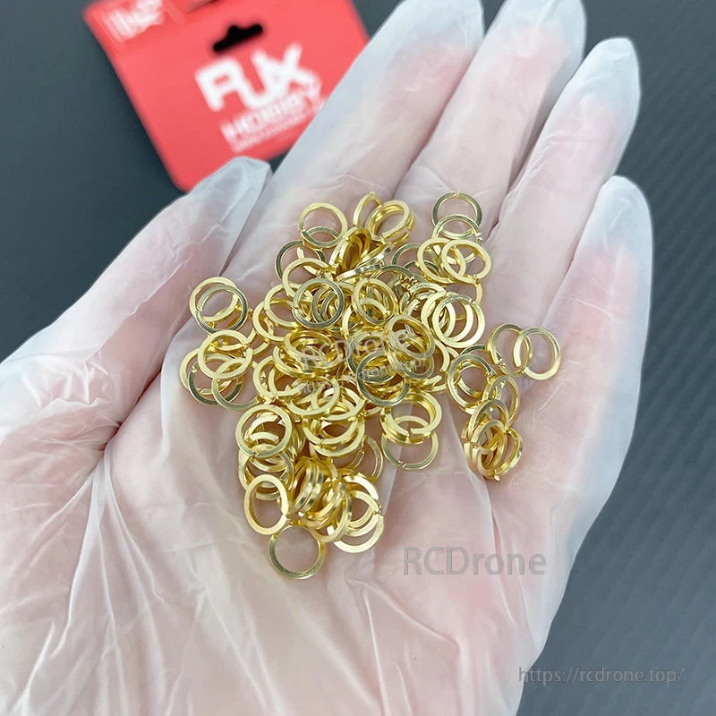 Gold-colored SMA nut tooth washers in a gloved hand, hardware gaskets for SMA female connectors