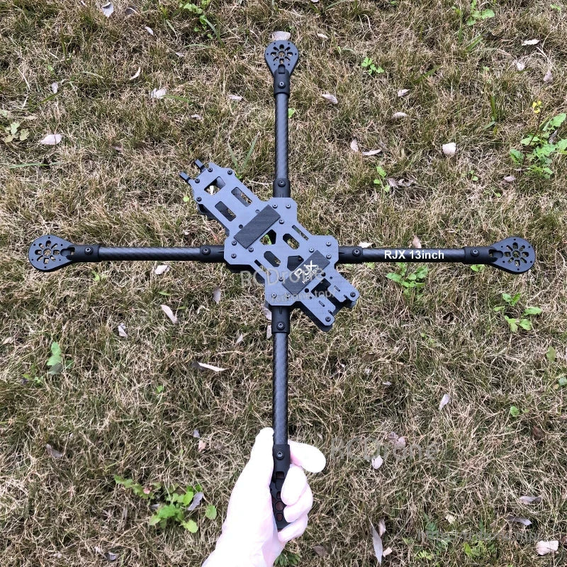 RJX 13 inch carbon fiber FPV racing drone frame with long arms and center plates, held over grass