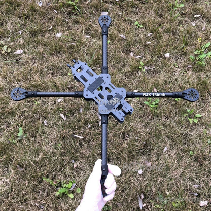 RJX 13 inch carbon fiber FPV racing drone frame with long arms and center plates, held over grass