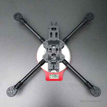RJX 13-inch carbon fiber FPV racing drone frame kit in X layout with four arms, shown on a digital scale