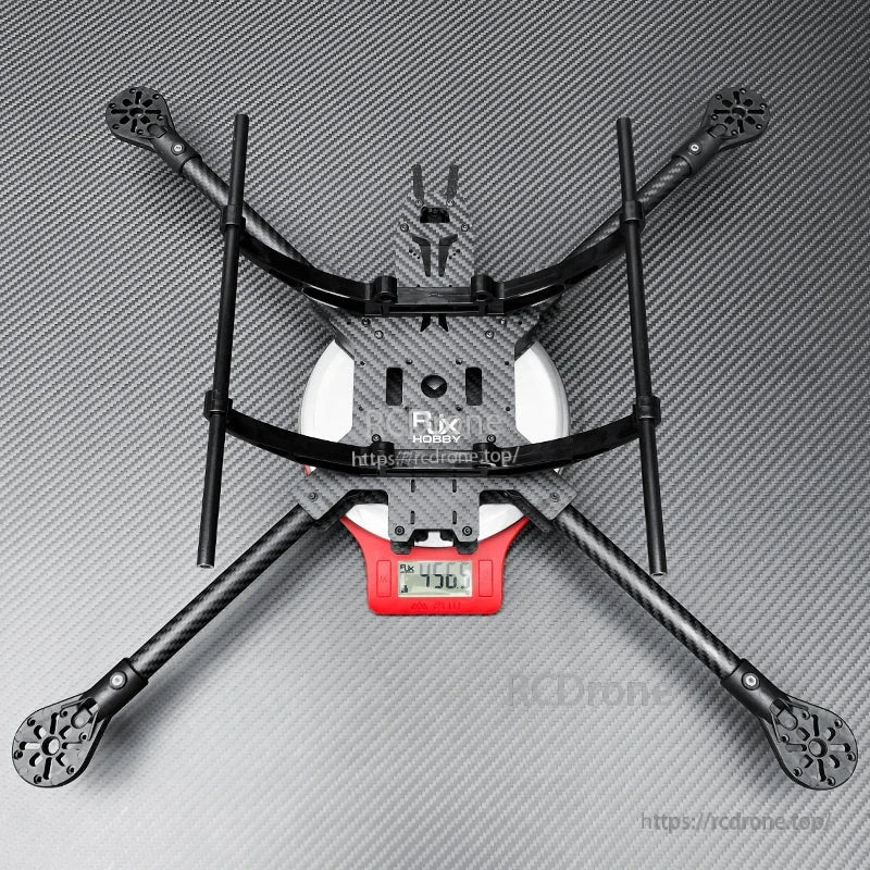 RJX carbon fiber quadcopter frame kit with long landing gear rods, shown assembled on a digital scale