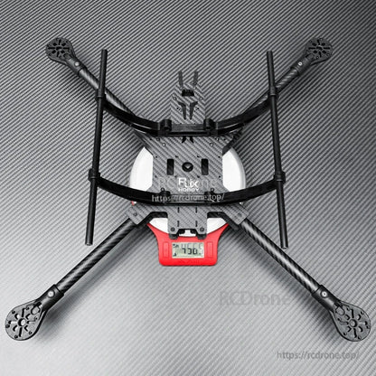 RJX carbon fiber quadcopter frame kit with long landing gear rods, shown assembled on a digital scale