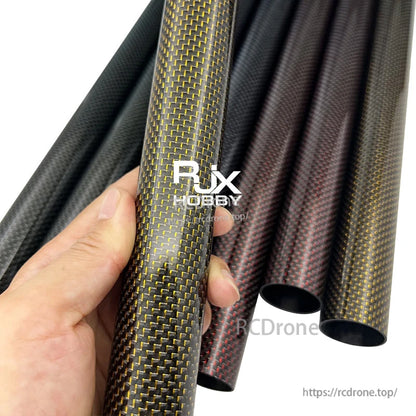 RJX 1pcs Colored 3K Carbon Fiber Tube, Hand holding colored 3K carbon fiber tube with woven pattern, with several hollow carbon fiber tubes in background