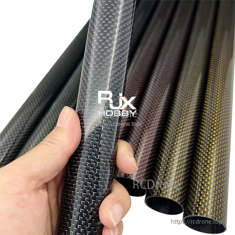 Hand holding RJX 3K carbon fiber tube with glossy woven finish, with multiple carbon tubes in the background