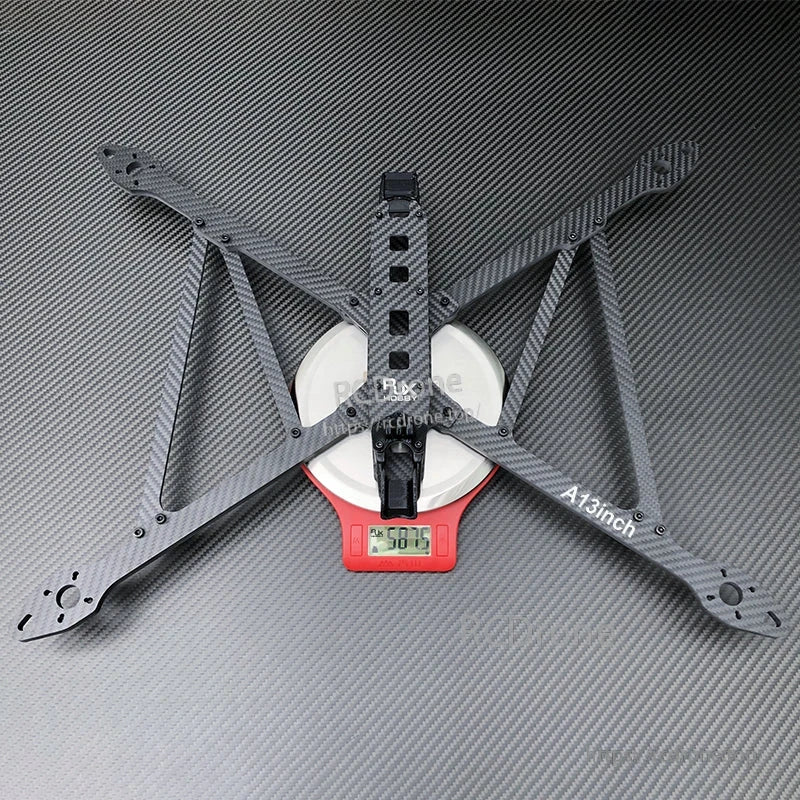 RJX A13 13-inch carbon fiber X-class FPV drone frame kit on a scale, with four wide arms and center plate