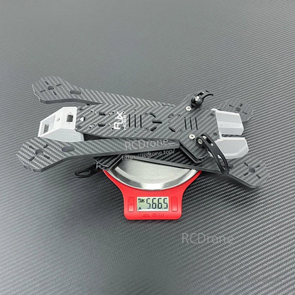 RJX A4 carbon-fiber FPV freestyle drone frame kit on a digital scale reading 566.5 g, with front camera mount