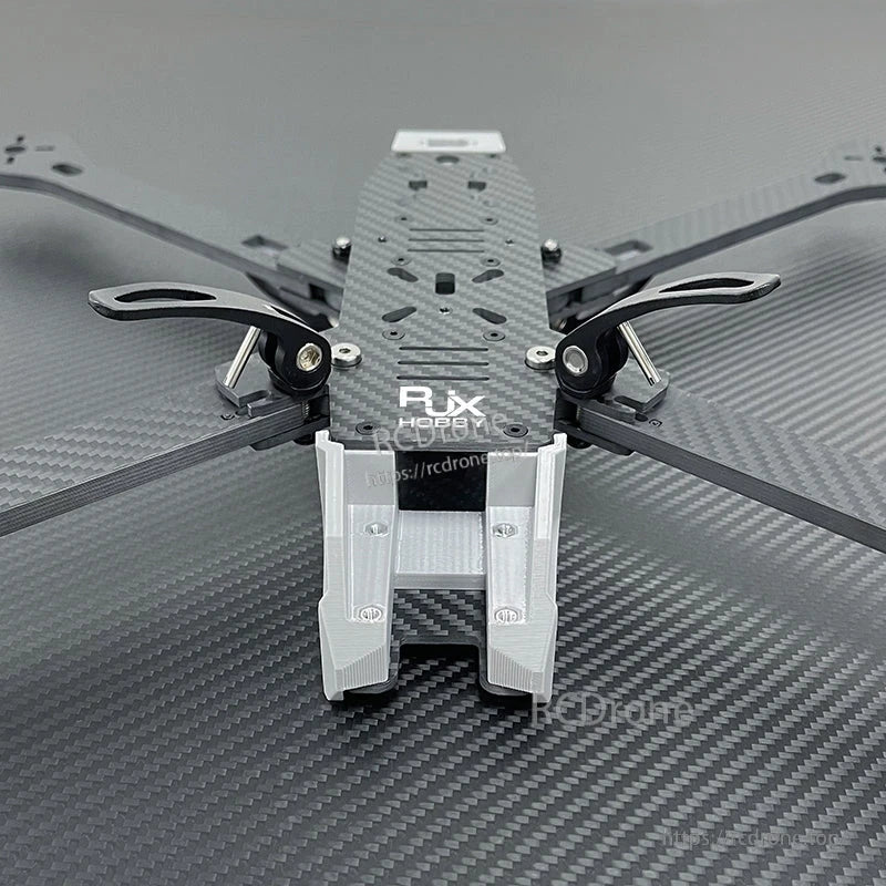 Close-up of RJX A4 carbon fiber FPV racing drone frame with metal standoffs and a 3D-printed front mount.
