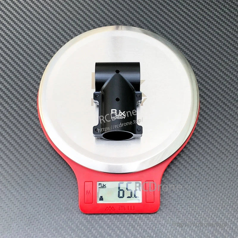 Black aluminum tee joint landing gear connector for RC drone, shown on a digital scale reading 65.2 g