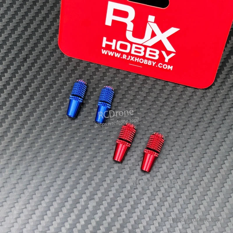 Four RJX aluminum gimbal thumb sticks in blue and red with knurled grip texture on a carbon fiber surface