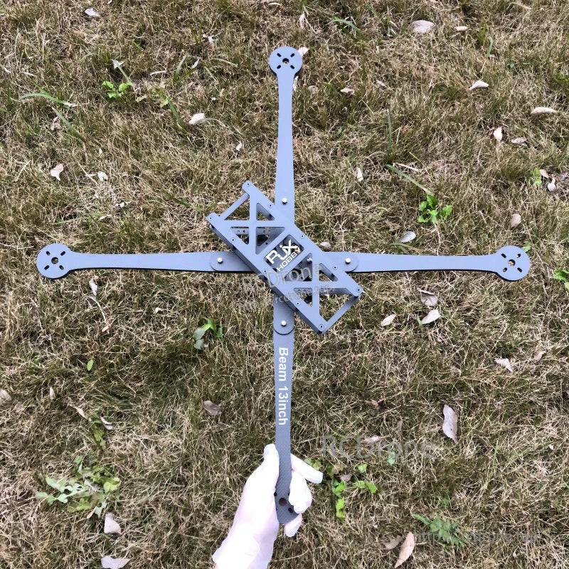 RJX Beam 13inch carbon fiber FPV racing drone frame kit with X arms and center plate laid on grass