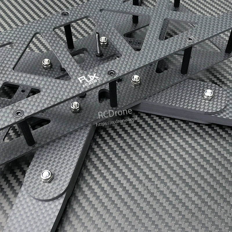 Close-up of RJX Hobby carbon fiber RC drone frame plates with standoffs and mounting hardware