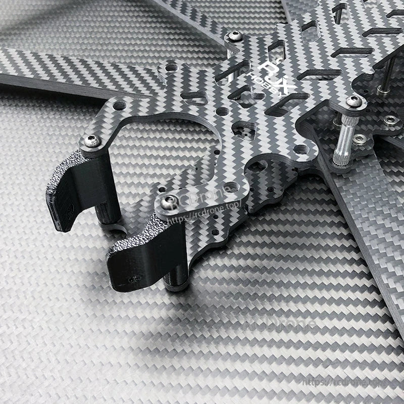 Close-up of carbon fiber FPV drone frame plates with black TPU mounts, aluminum standoffs, and screws
