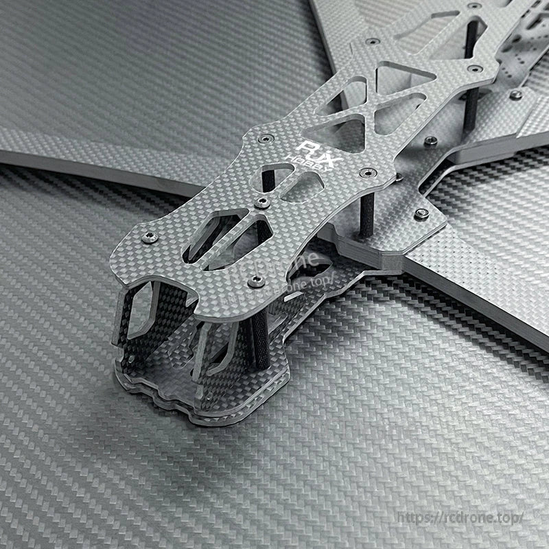 Close-up of RJX carbon fiber FPV racing drone frame kit with layered plates, cutouts, and standoffs.