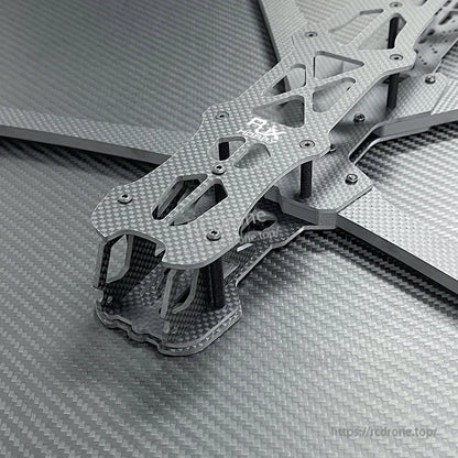 Close-up of RJX carbon fiber FPV racing drone frame kit with layered plates, cutouts, and standoffs.