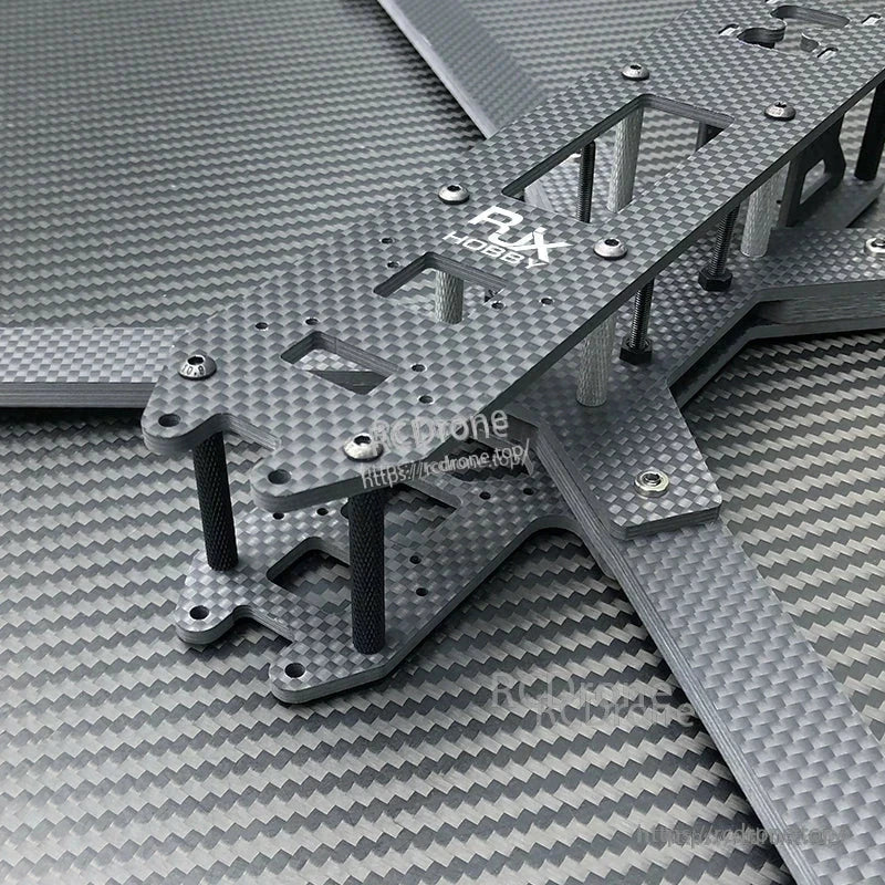 Close-up of RJX carbon fiber FPV drone frame kit plates with cutouts, standoffs, and hardware installed