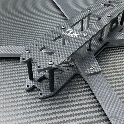 Close-up of RJX carbon fiber FPV drone frame kit plates with cutouts, standoffs, and hardware installed