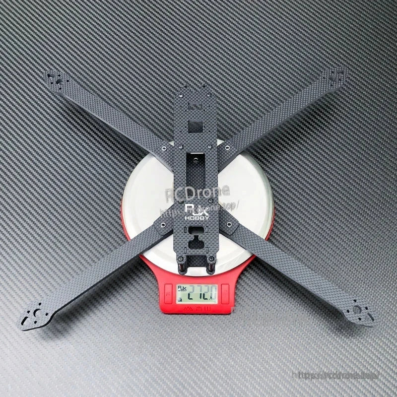 Carbon fiber X-frame base plate for a 10-inch FPV racing drone, shown on a digital scale reading 272.0