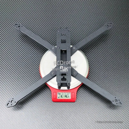 Carbon fiber X-frame base plate for a 10-inch FPV racing drone, shown on a digital scale reading 272.0