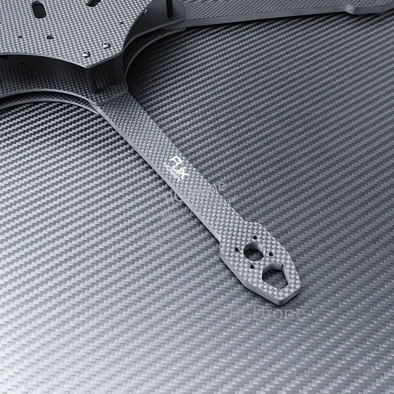 Close-up of RJX carbon fiber FPV drone frame arm with motor mount holes and plate edge