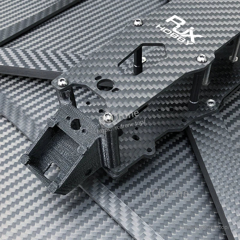 Close-up of RJX Hobby carbon fiber FPV drone frame kit with stacked plates, standoffs, screws, and a front mount