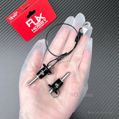 Two RJX stainless steel ball lock pins with pull rings and lanyard, displayed on a gloved hand.