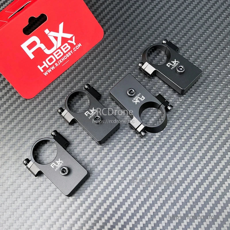 RJX UAV Drone Tube Mount, Four RJX Hobby black aluminum drone tube mounts with circular clamps and screw fasteners on carbon-fiber surface