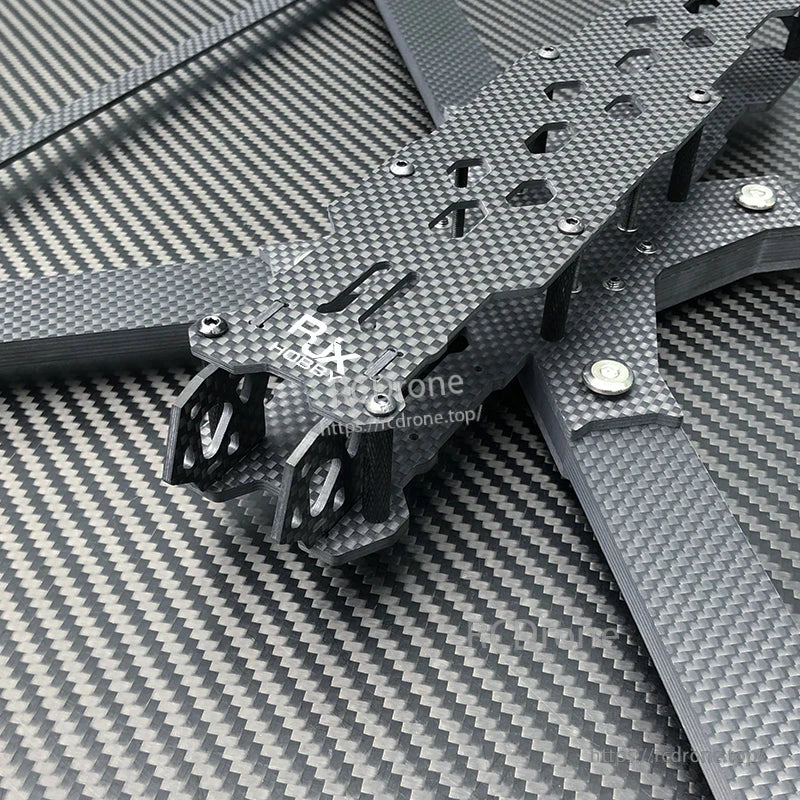 Close-up of RJX carbon fiber FPV drone frame plates and arms with mounting holes, cutouts, and metal standoffs